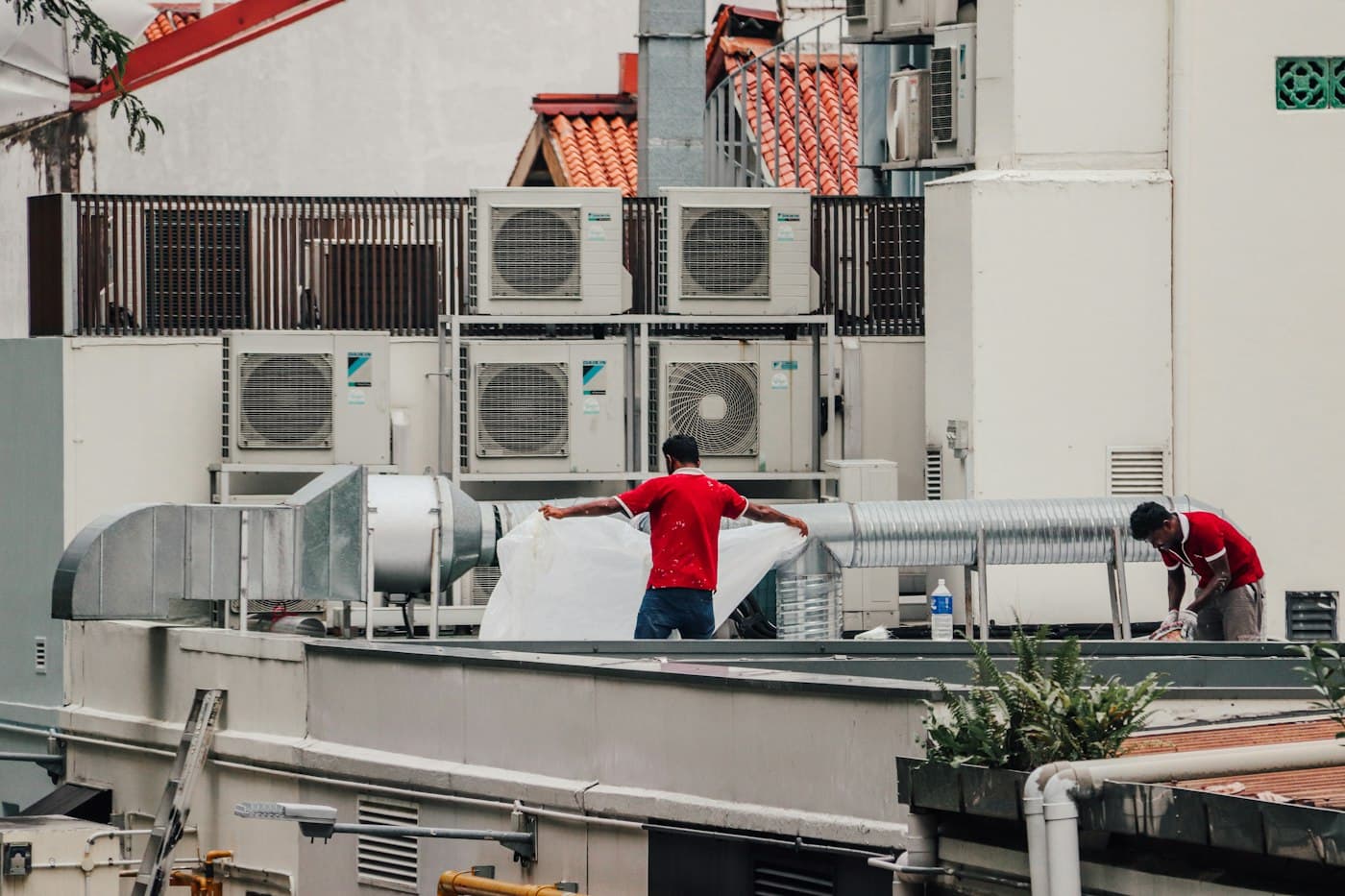Technicians work among rows of air conditioning units on a commercial rooftop