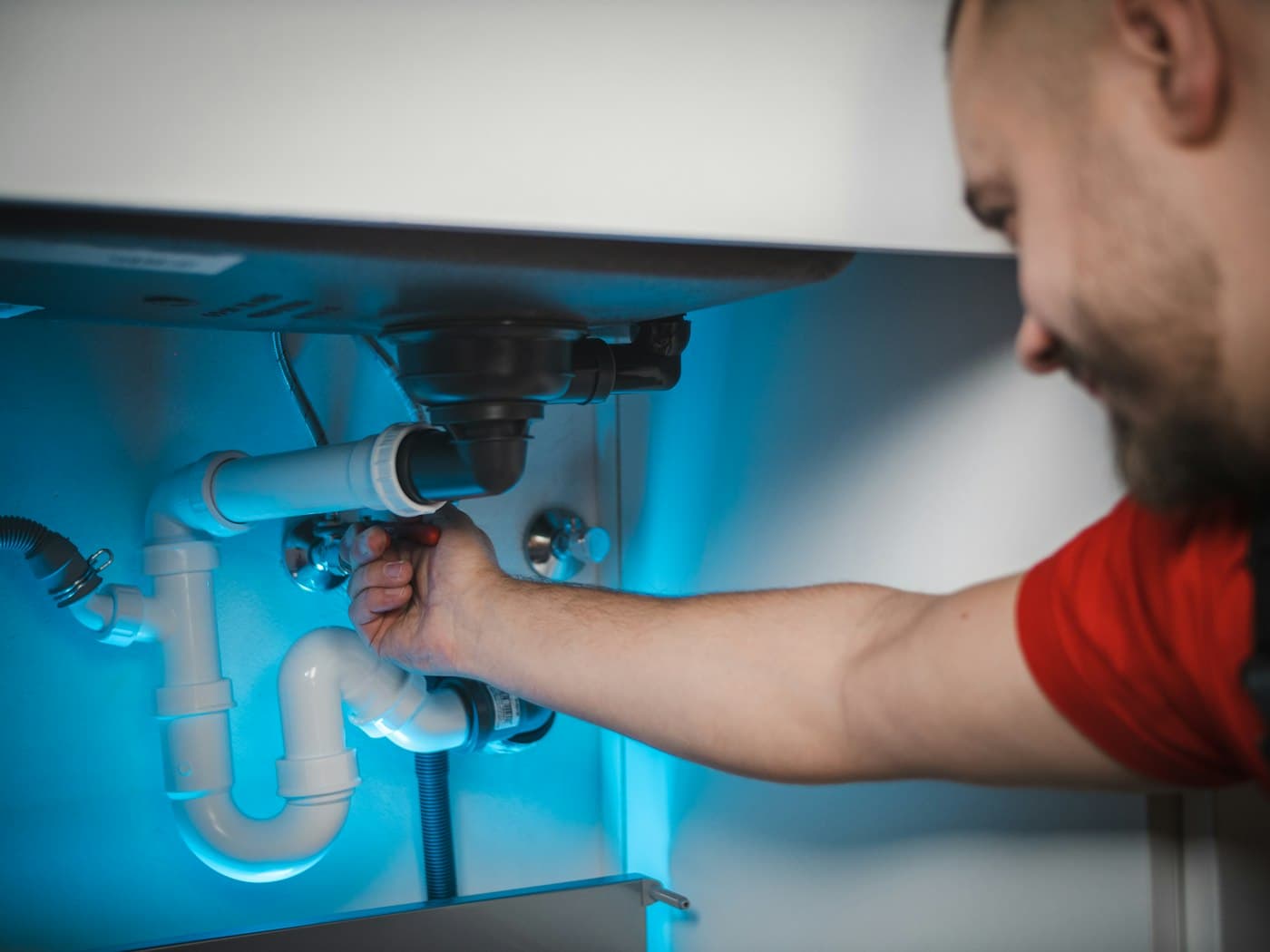 A plumber fits a drain trap under a basin